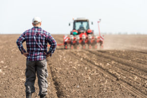 young farmer on farmland with tractor in background